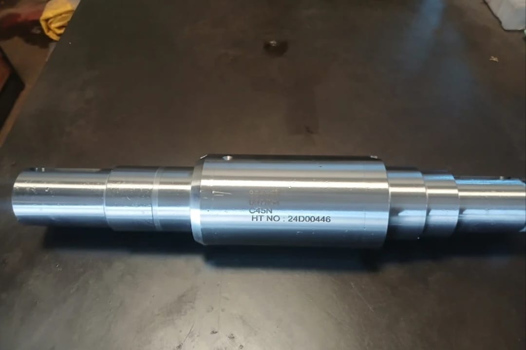 A precision-turned multi-stepped steel shaft with laser-etched heat treatment specifications and part numbers